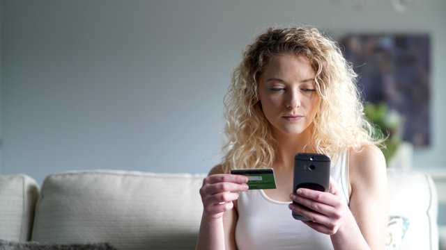 Attractive blond woman shopping online with smartphone and credit card