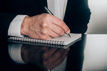 cropped shot of businessman writing in notepad