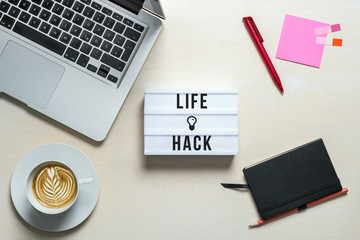 Life hack written on lightbox in office as flatlay