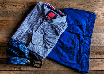 male set on a wooden background: denim shorts, shirt and belt.