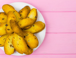 Rusks on a white plate on a pink wooden background.