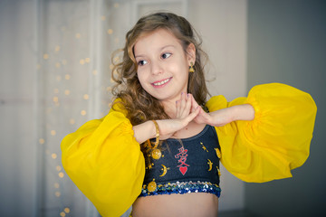 dancer girl. Girl, closing with a yellow Indian handkerchief. Eastern dance. Portrait of a smiling girl dancer in studio. Dancing teenage girl in a beautiful yellow attire