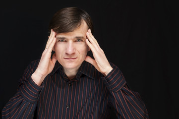 A middle-aged man with a sad, angry face holds his hands on his head