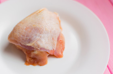 Raw chicken thighs on a white plate.