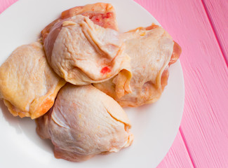 Raw chicken thighs on a white plate.