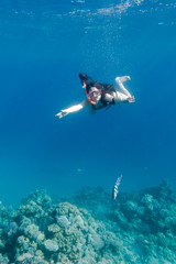 Girl in swimming mask diving in Red sea near coral reef