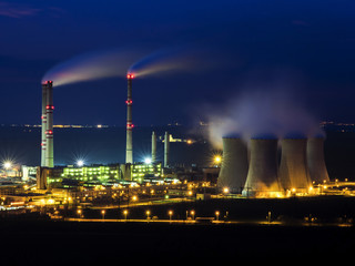 A coal-fired power station in the distance at night. Pocerady, Czech republic