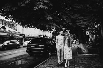 Black and white photo on which a loving couple walks around the city on a beautiful spring day along the streets of the old city among the big chestnut trees