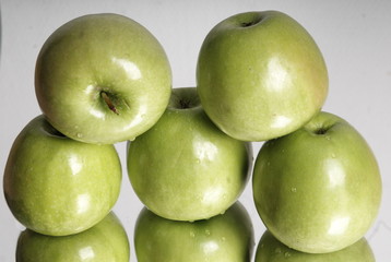 Fresh ripe green apples with green leaves as background