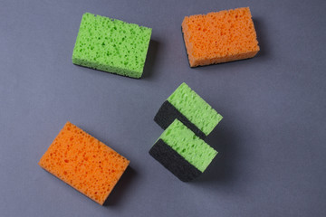 Orange and green sponges for dishes on grey background