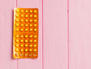 Yellow pills in a blister on a pink background.