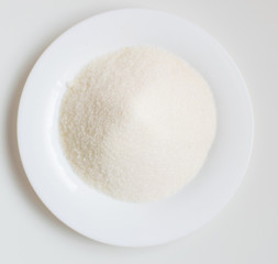 Sugar on a white plate on a white background.