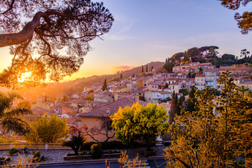 Vue panoramique sur le village de Bormes les Mimosas. Arbres de mimosa en fleurs au premier plan. Coucher de soleil. Provence, France.