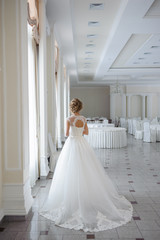 Fototapeta na wymiar Beautiful bride in wedding dress before wedding ceremony in great hall