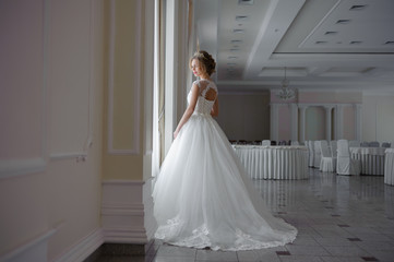 Fototapeta premium Beautiful bride in wedding dress before wedding ceremony in great hall