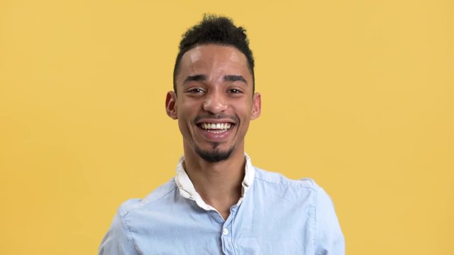 Portrait of happy guy being in good mood and laughing, while isolated over yellow background in studio. Concept of emotions