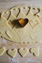 Baking Heart Shaped Cookies
for valentine's day, over a wooden  background,with cookie cutter with heart shape top view