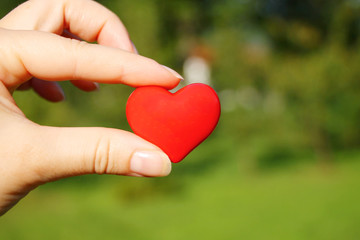 Fototapeta na wymiar Small red heart in woman's hand
