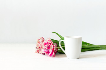 Fototapeta na wymiar White cup mockup. Empty mug and tulips on wooden white background