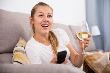 Girl is resting with wine and watching TV