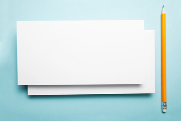 Blank layout of a greeting card on a blue background with a pencil.