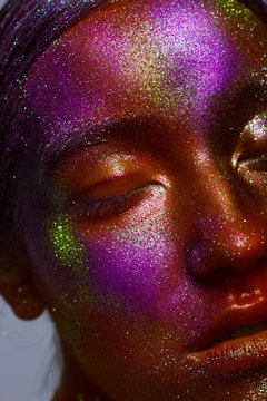 Body art. conceptual make-up. gold orange purple skin beauty girl. Close-up fashion portrait of woman face in colored spotlights