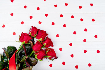 Top view of bouquet red roses and paper hearts on white wooden background, copy space. Greeting card mockup for Saint Valentines Day, Womens Day (March 8), Mothers Day. Love, wedding concept, flat lay