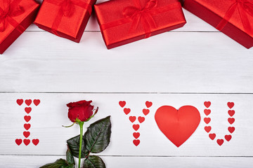 Holiday background with gift boxes, sign I Love You made from red paper hearts and rose, copy space. Greeting card for Valentines Day, Womens Day. Symbol of love. Love concept, Top view, flat lay