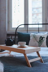 Breakfast in bed. Teapot with tea and mug on the table