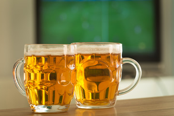 Beer mugs on the background of the TV match