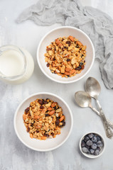 Homemade granola in white bowls on gray concrete background, top view, flat lay.