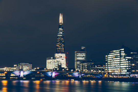 London skyline at night with shard building and reflections on River Thames