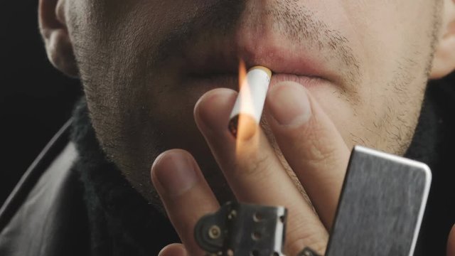 Close up of a brutal man smoking a cigarette at black background