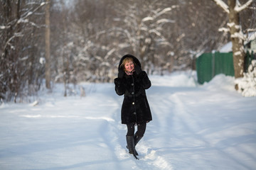 Full-length portrait of a young woman in snowy weather outdoor.