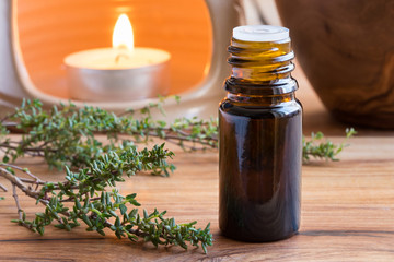 A dark bottle of thyme essential oil with fresh thyme twigs