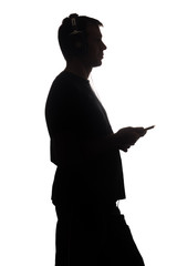 Silhouette of a young man with a smartphone with headphones