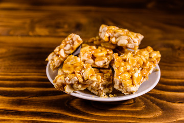 Ceramic plate with peanut brittles on wooden table.