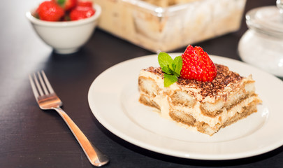 Homemade tiramisu cake decorated with strawberries Italian cuisine, Selective focus