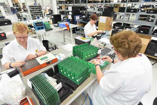 Frauen in einem Werk für Elektronik montieren Leiterplatten // Women in a factory for electronics assemble printed circuit boards