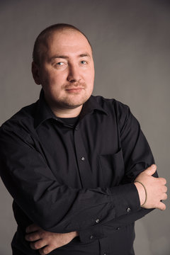 portrait of man in black shirt isolated on gray studio background posing to the camera
