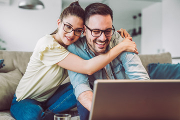 Happy couple with laptop spending time together at home