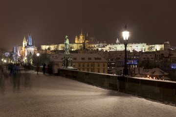 Fototapeta na wymiar Night snowy Prague Lesser Town with gothic Castle from Charles Bridge and its baroque Statues, Czech republic