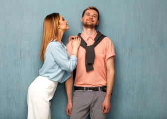 Fashion girl and guy in outlet clothes posing on a blue background