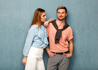 Fashion girl and guy in outlet clothes posing on a blue background