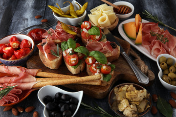 Italian antipasti wine snacks set. Cheese variety, Mediterranean olives, pickles, Prosciutto di Parma, tomatoes, artichokes and wine in glasses