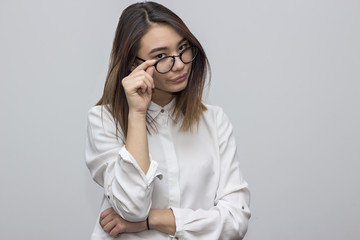 Indoor portrait of beautiful brunette asian woman holding black glasses. Young student or businesswoman concept. Selective focus and shallow DOF