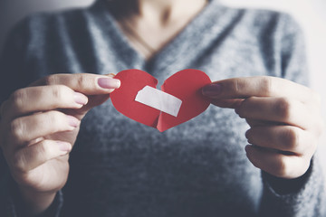 Woman holding broken heart fixed by plaster