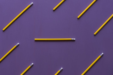 Pencils with eraser tops on purple background - Wooden pencils with eraser tops arranged parallelly and only  one in horizontally, out of context, with space for text, on a purple background.