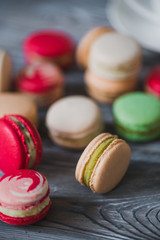 Macarons on rustic wood table, French candy meringue-based made with egg white, icing sugar, granulated sugar, almond powder or ground almond and food coloring