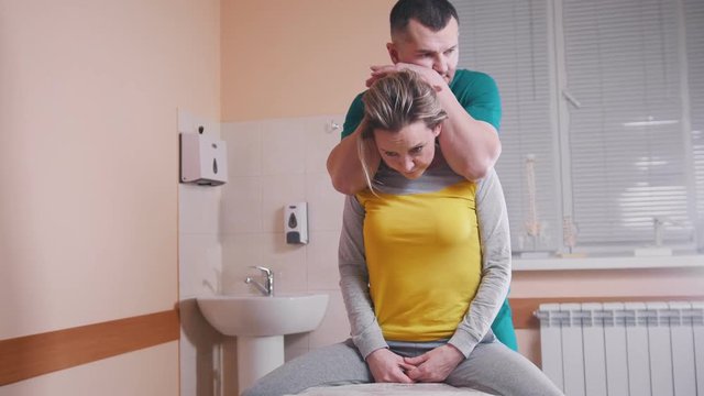 Manual therapist massaging a young woman bending her neck